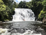 A hidden waterfall cascading into the river with rafters pausing nearby to appreciate the view.