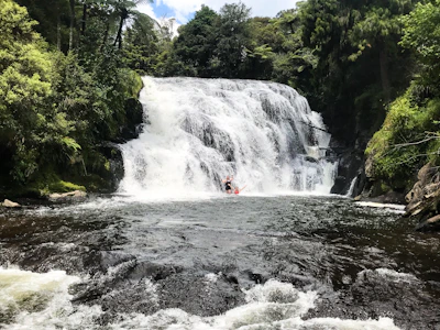 A hidden waterfall cascading into the river with rafters pausing nearby to appreciate the view.