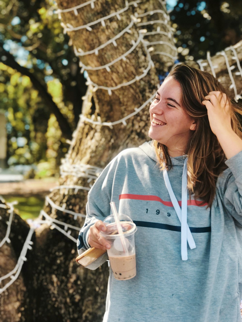 プラスチックカップを持つグレーのプルオーバーパーカーの女性