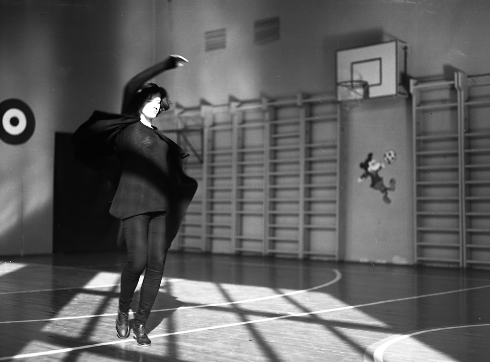 バスケットボールコートに立つ女性のグレースケール写真
