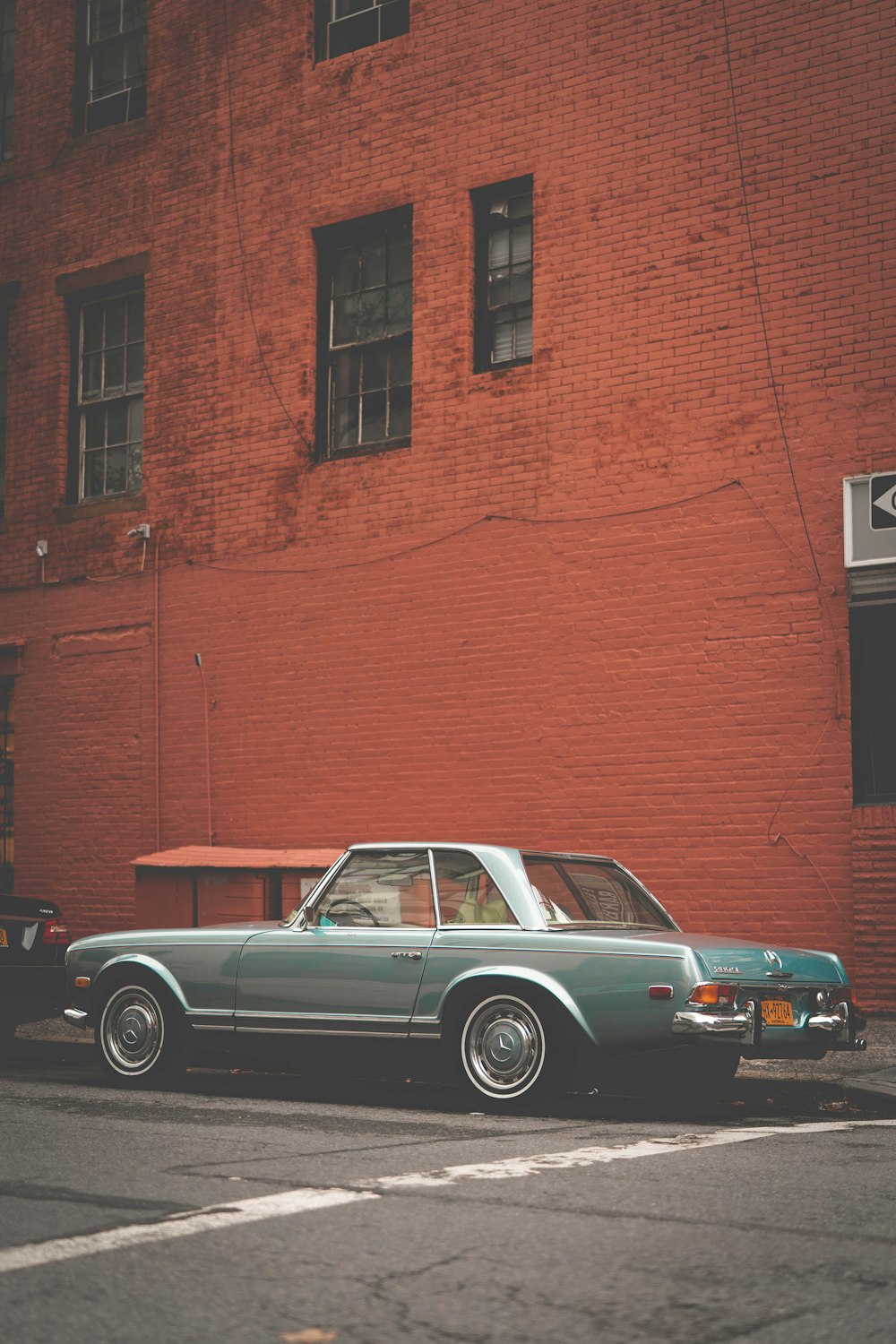 parked gray coupe beside brown concrete building