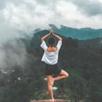 woman standing on rock facing forest