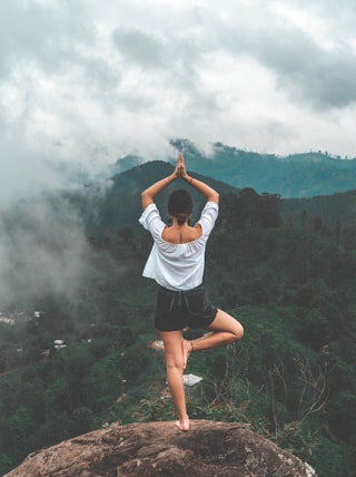 woman standing on rock facing forest