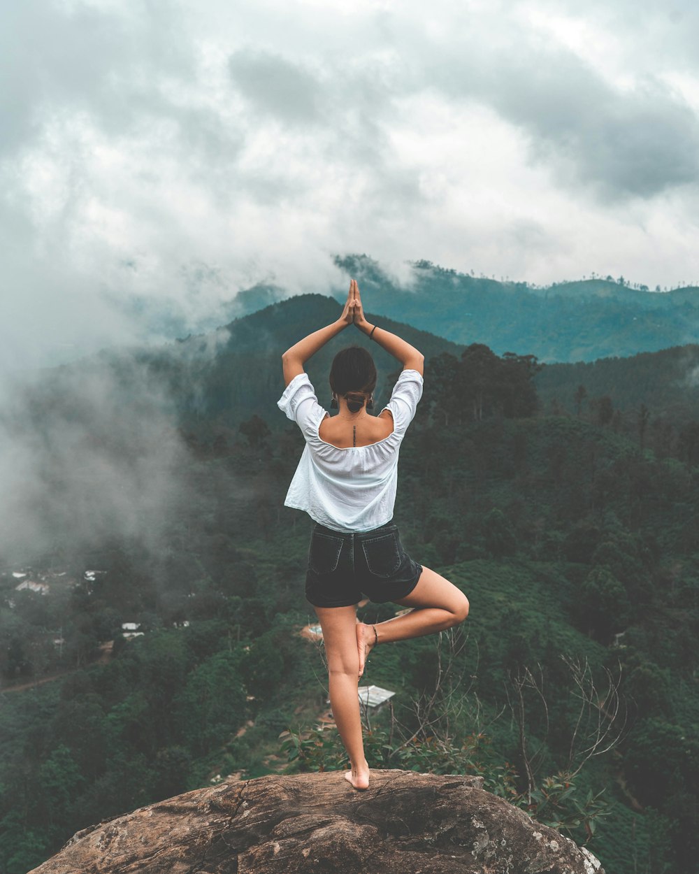 woman standing on rock facing forest