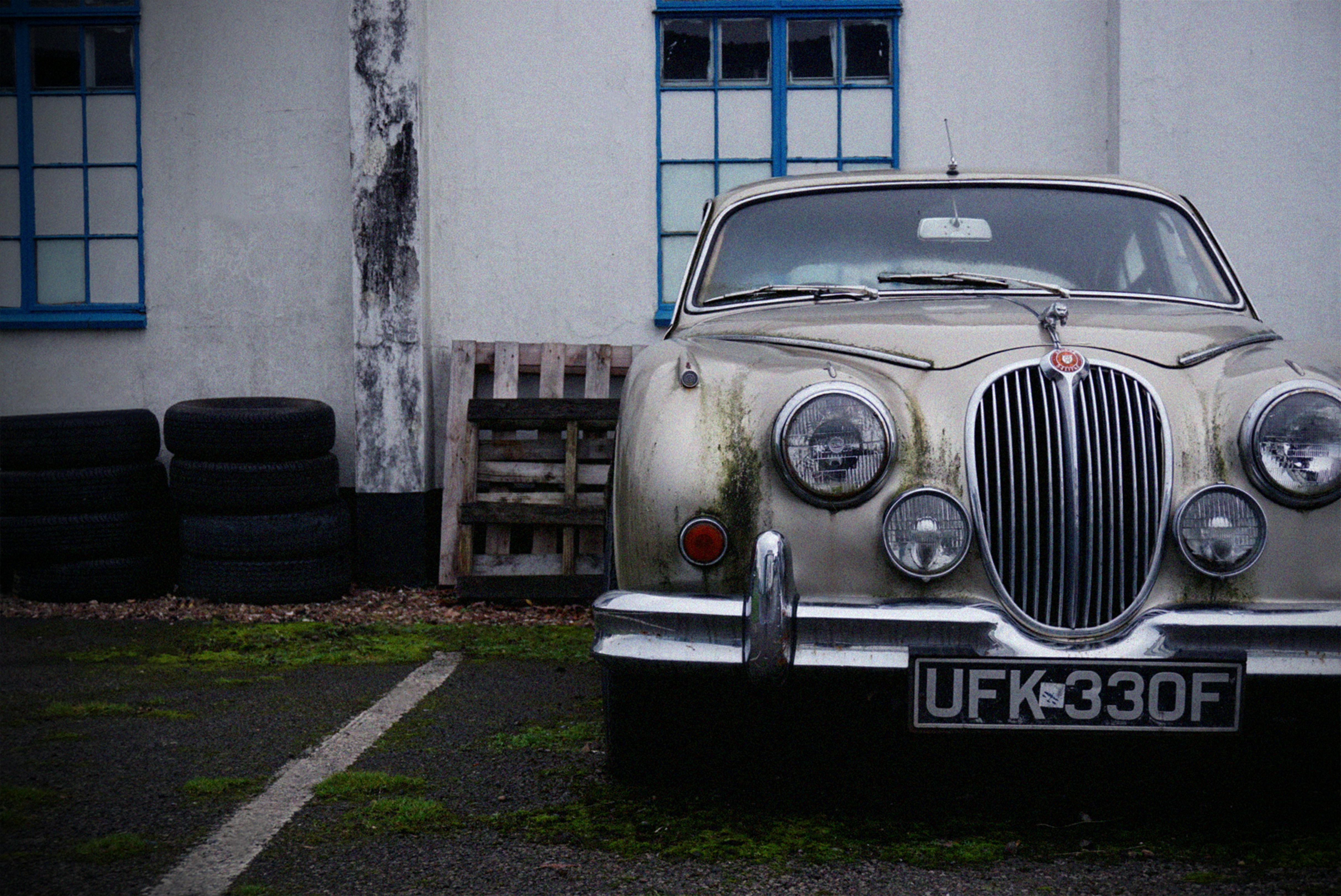 vintage grey car parked near white building during daytime