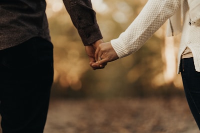 Close-up of a mother and daughter holding hands, both dressed in soft pastel sweaters.