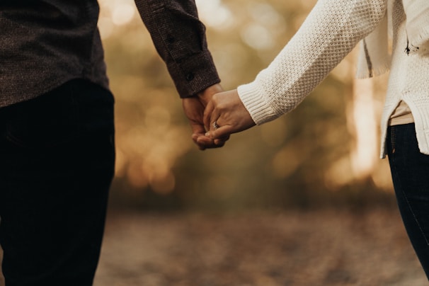A serene scene of a couple holding hands surrounded by warm earth tones and soft golden light.