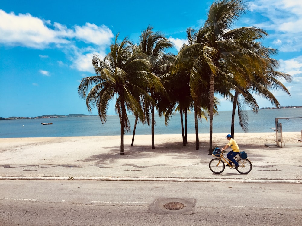 homem andando de bicicleta perto da praia durante o dia