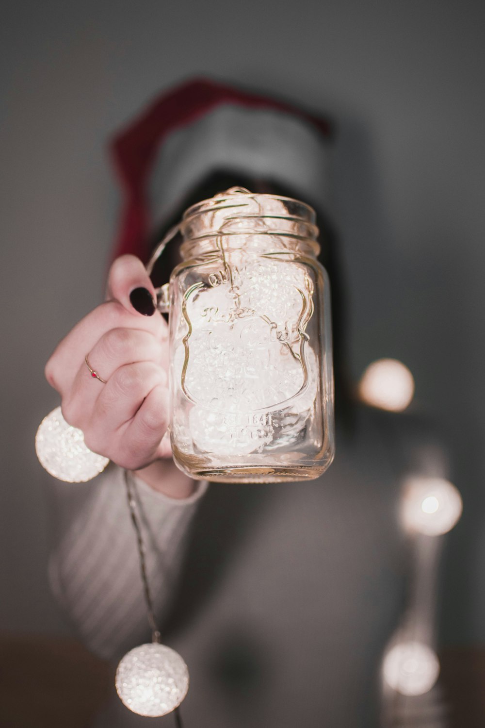 person holding glass mug with string lights