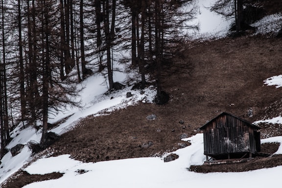 A cozy mountain cabin with spring snow melting around it, inviting participants to a retreat.