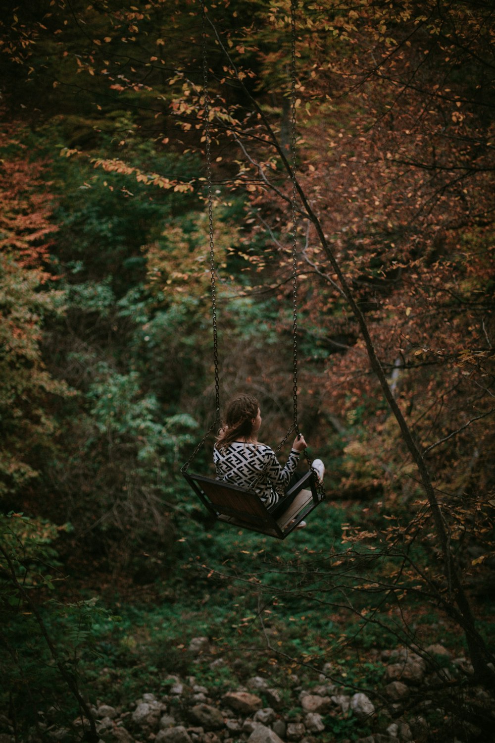 fille sur la balançoire entourée d’arbres