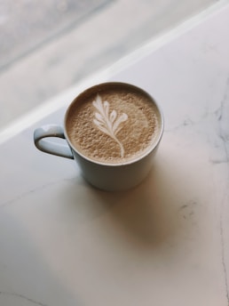 A modern minimalist coffee cup with natural green leaves background