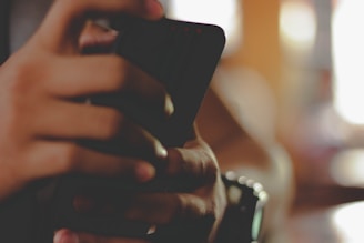 Hands gently holding a phone with a soft background.