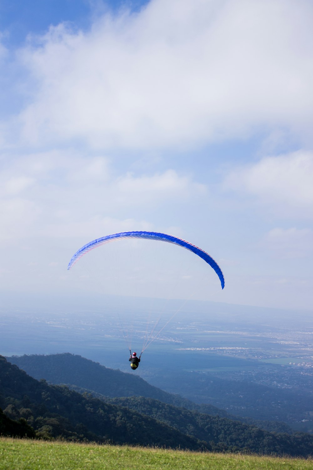 Hombre con paracaídas cerca de la montaña y el pueblo