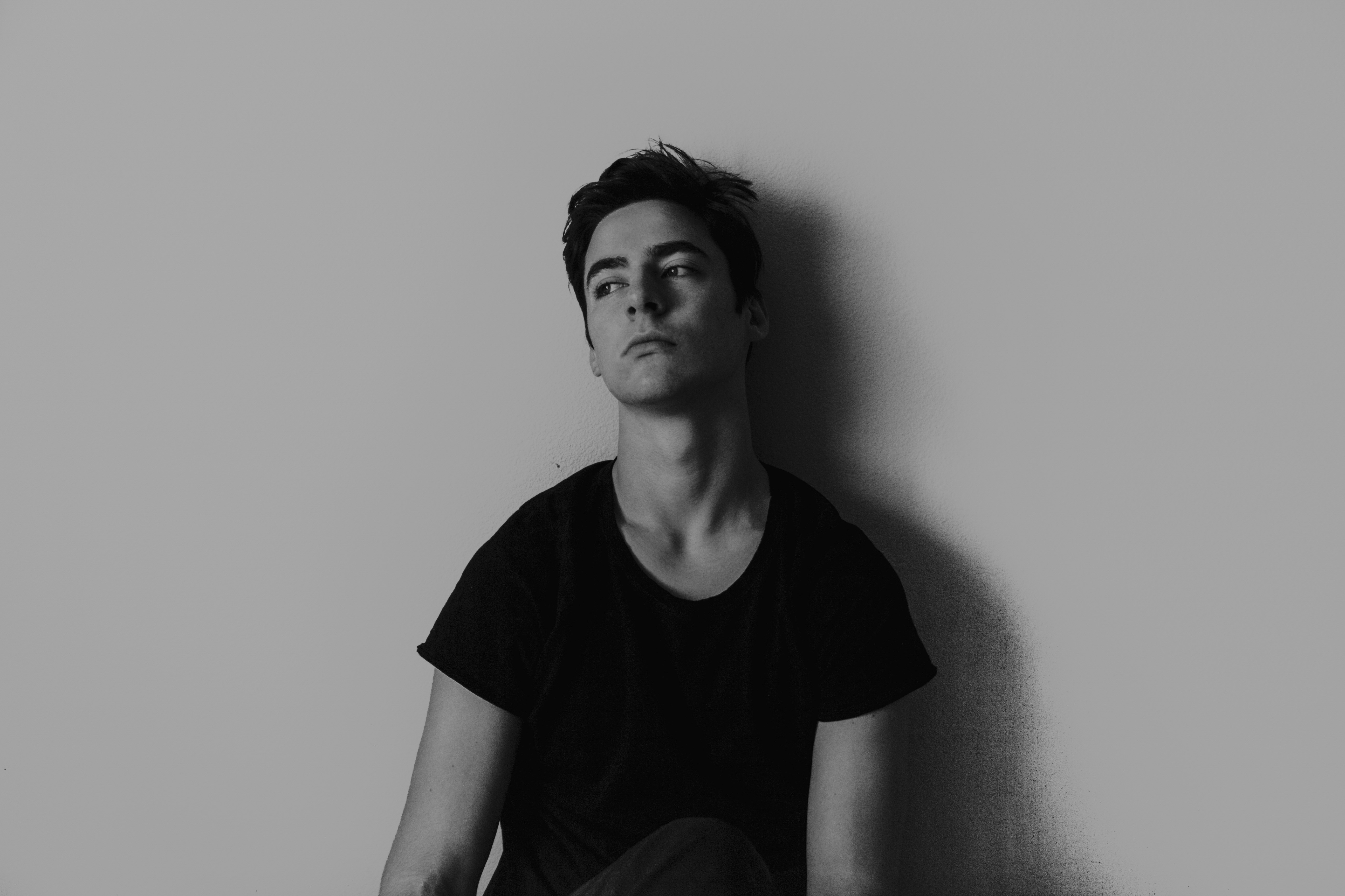 grayscale photography of man leaning on wall