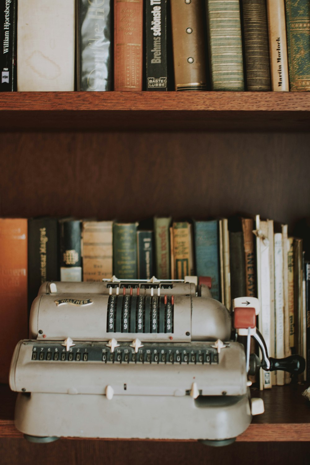gray typewriter on book shelves