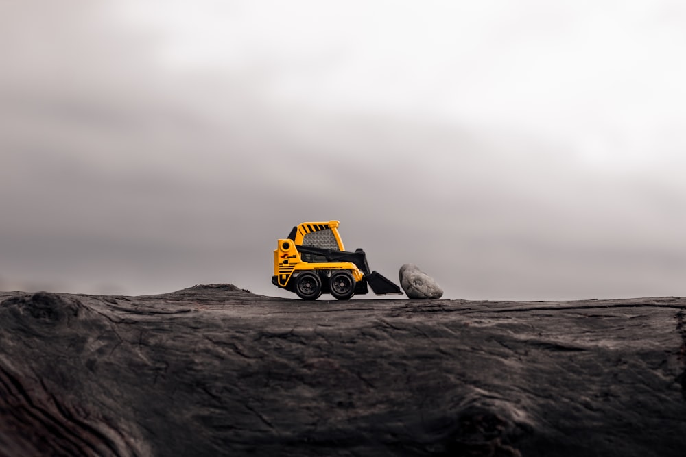 yellow skid steer loader in front of stone