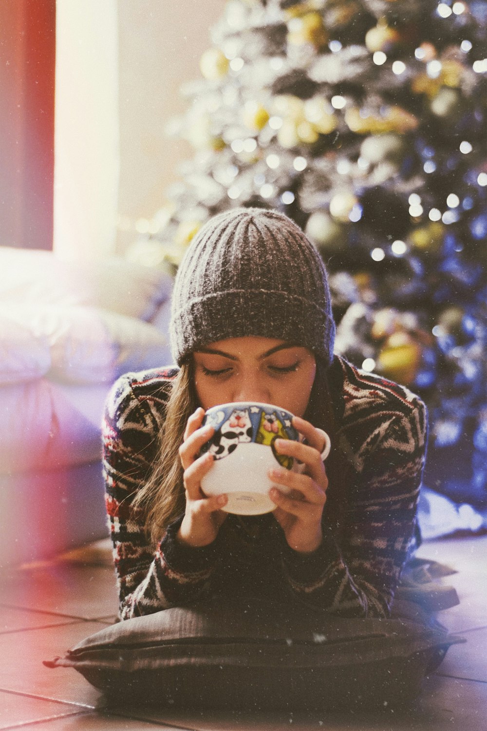 woman lying on floor while holding mug