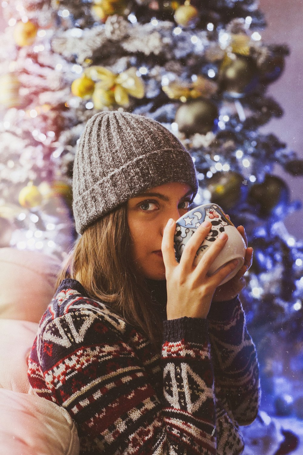 femme buvant dans une tasse près de l’arbre de Noël