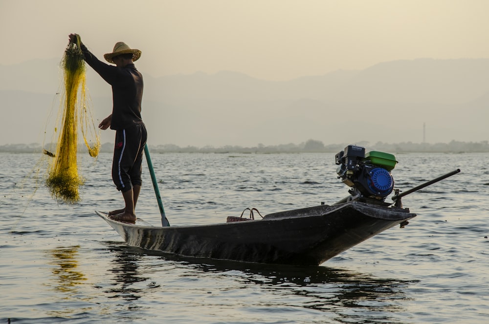 man holding fish net standing on boat