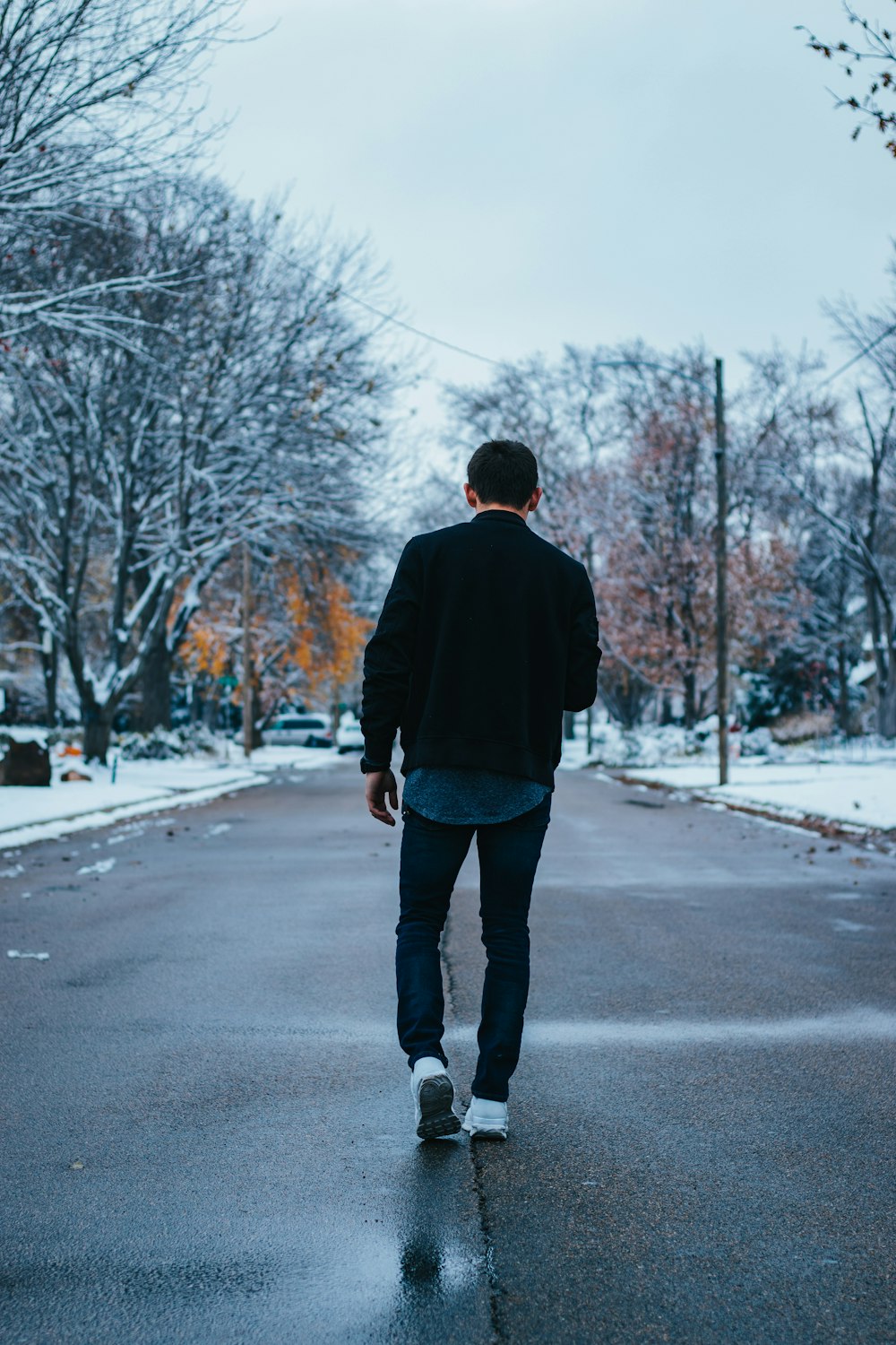 man walking on road near bare trees during daytime