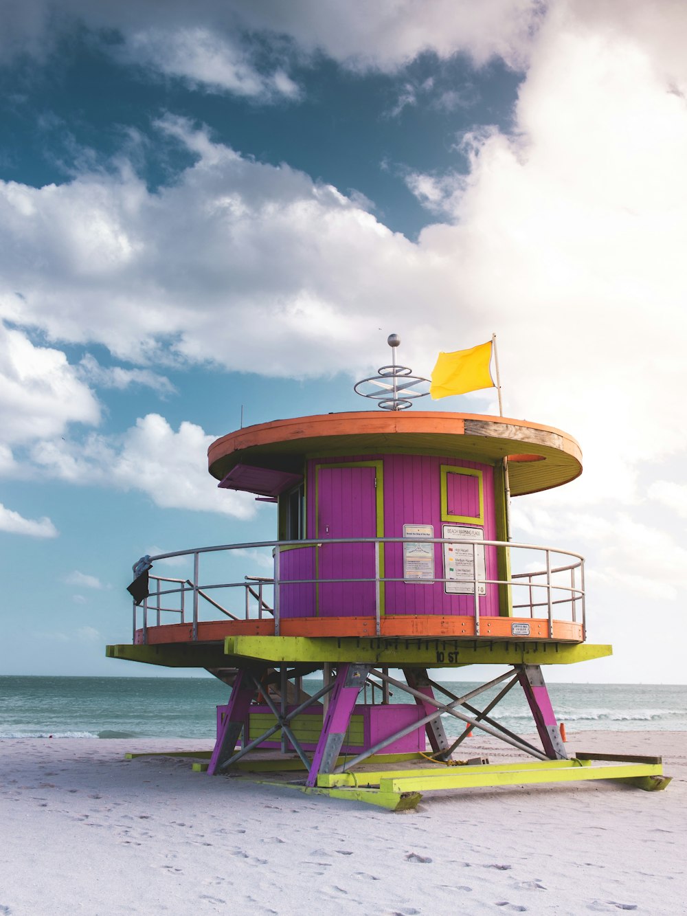 pink and yellow lifeguard tower near body of water