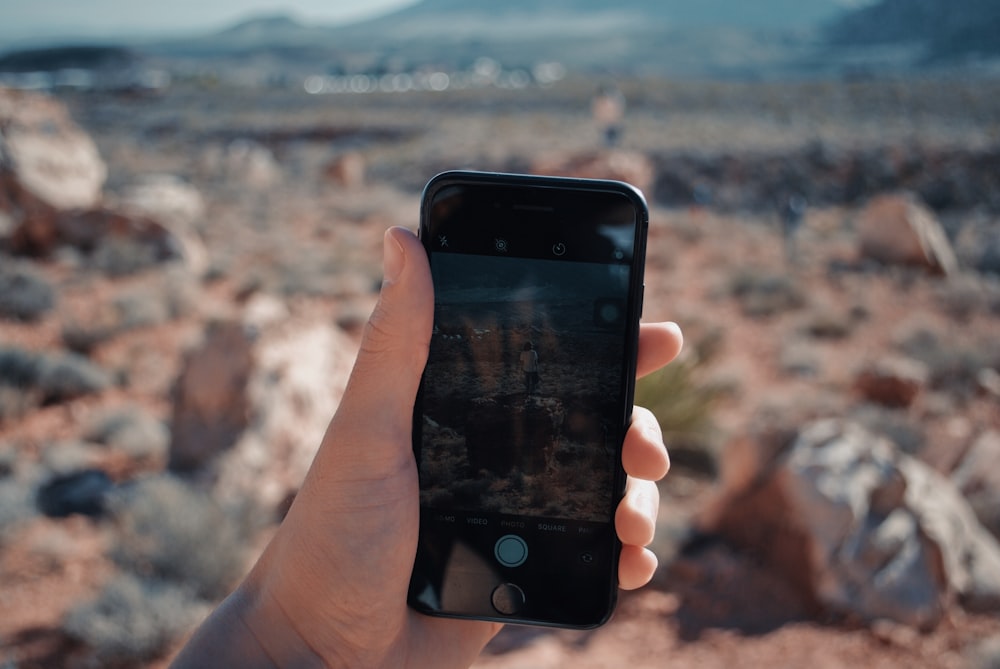 person holding iPhone taken photo of mountain during daytime