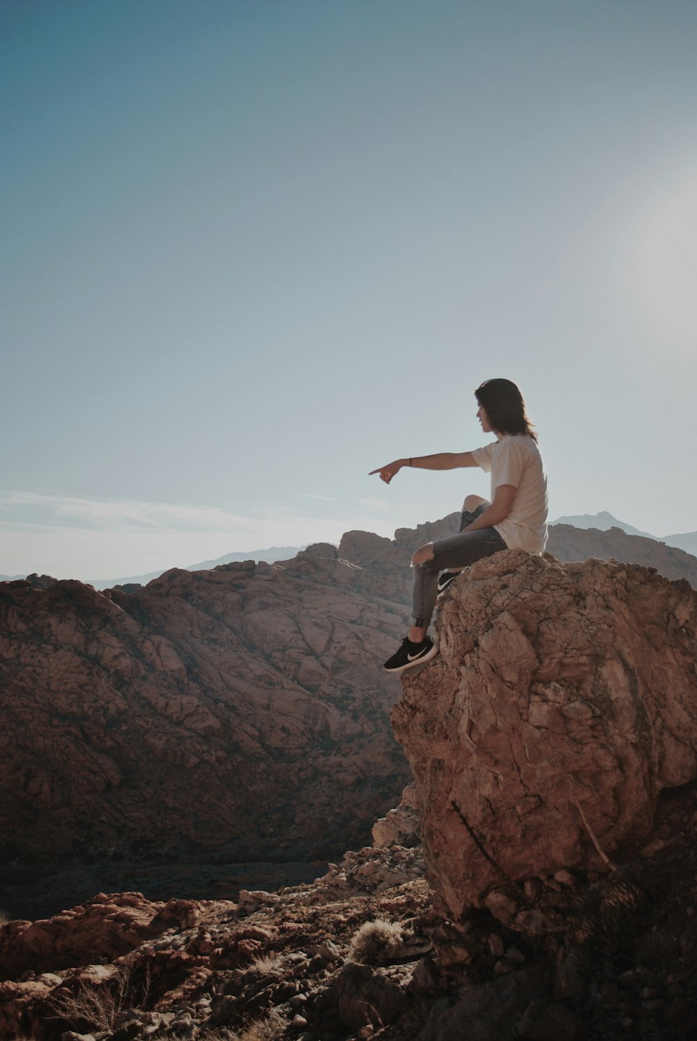 man sitting on rock under blue sky