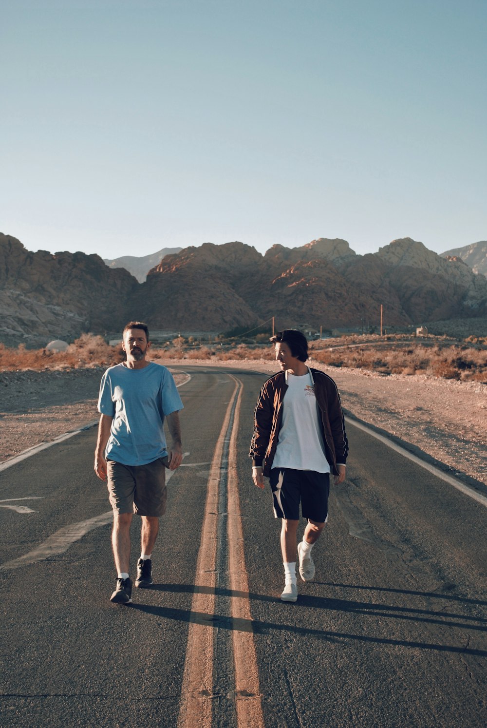 two men jogging on concrete road at daytime