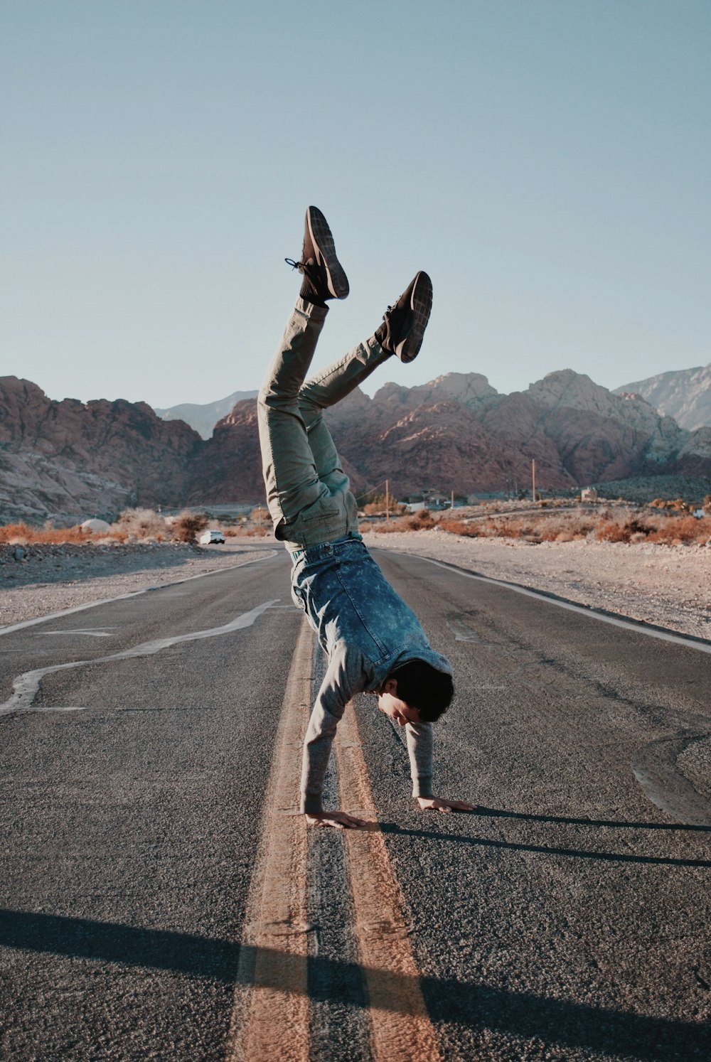 man doing upside down pose on road