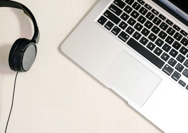 High-quality wireless headphones resting on a minimalist desk beside a laptop.
