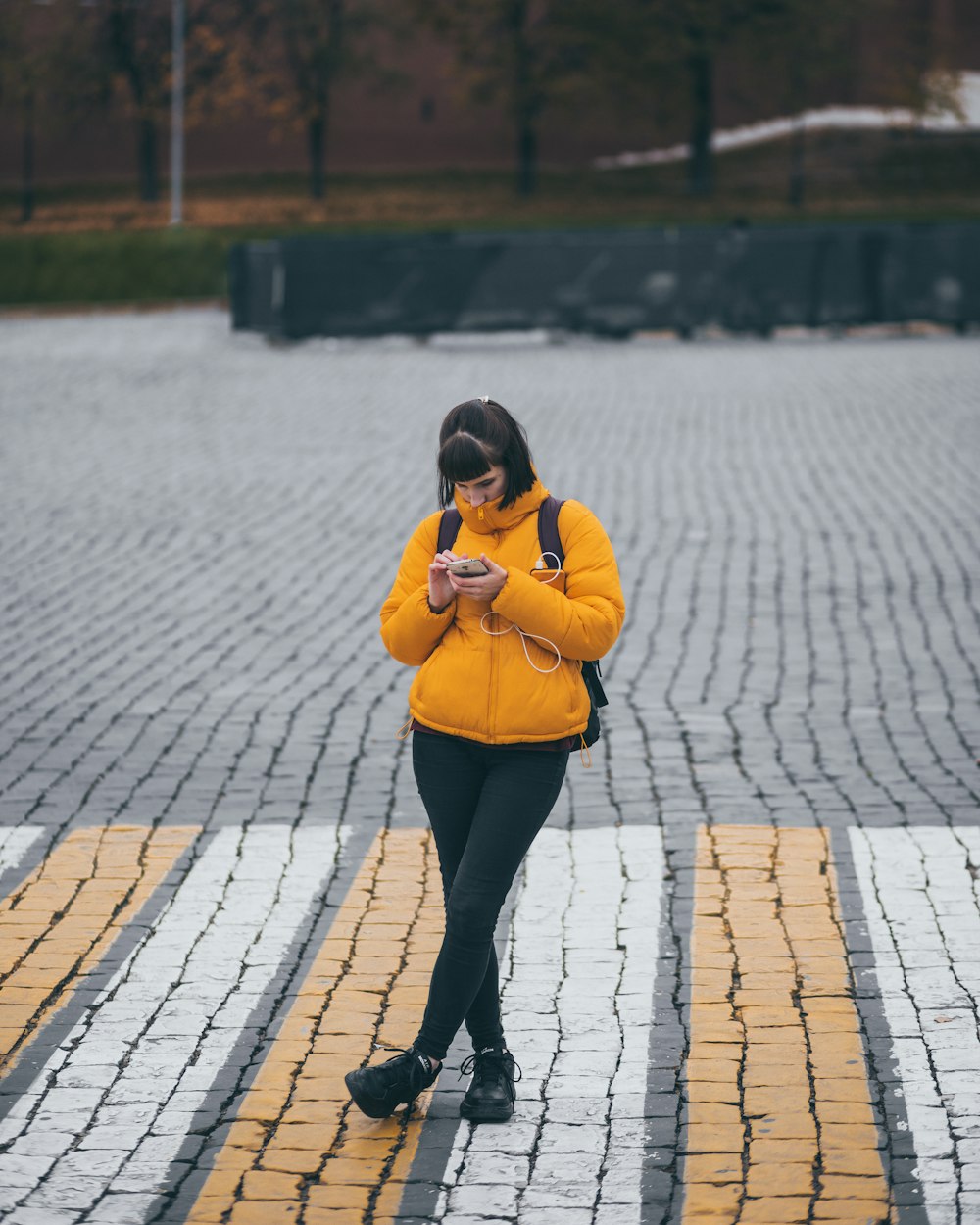 woman in yellow jacket holding smartphone