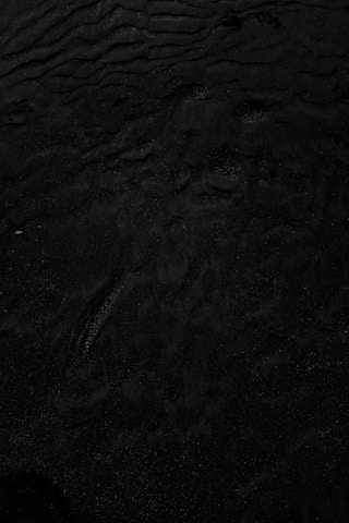 a black and white photo of water and sand
