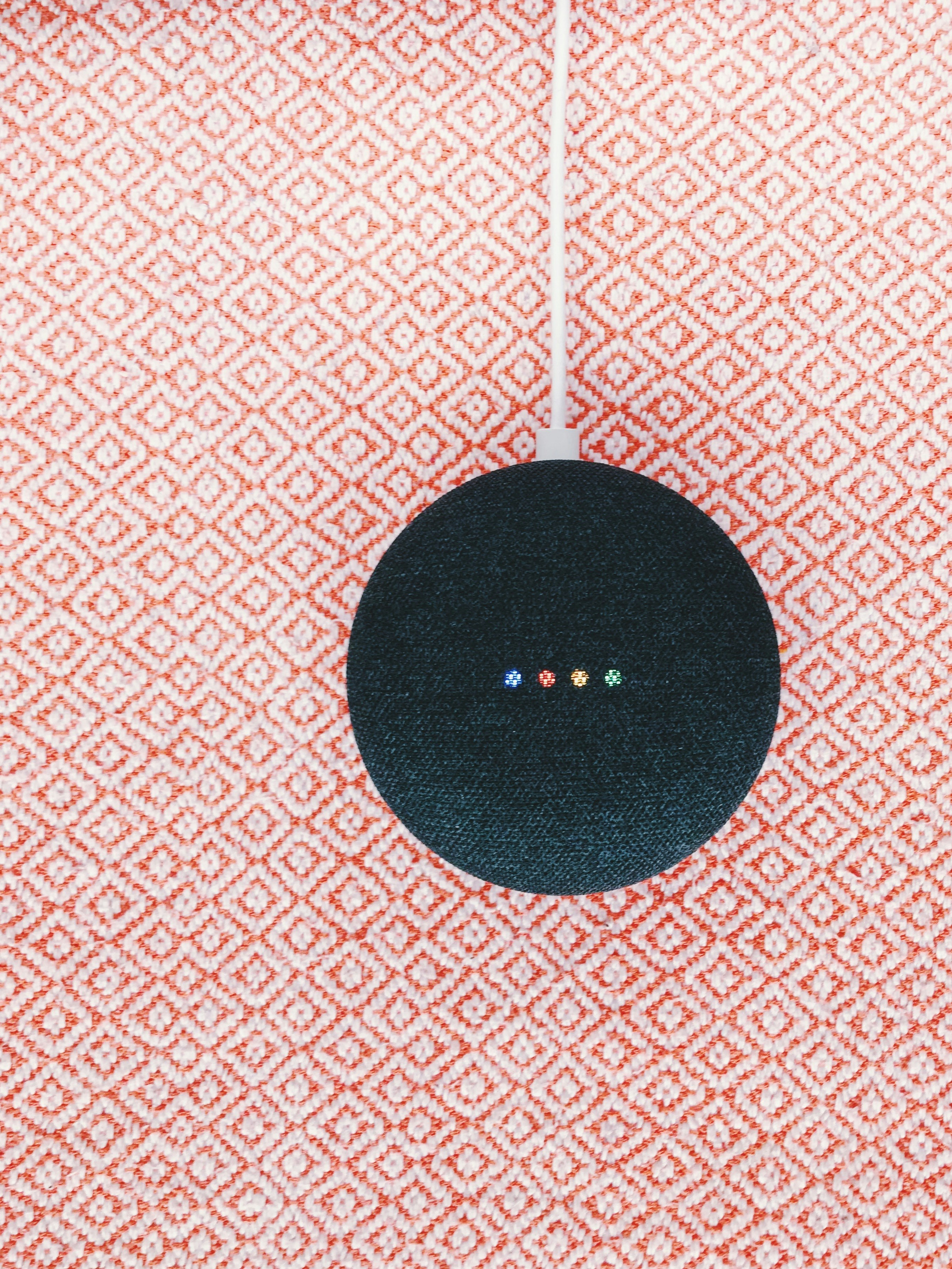 black Google Home Mini on pink textile