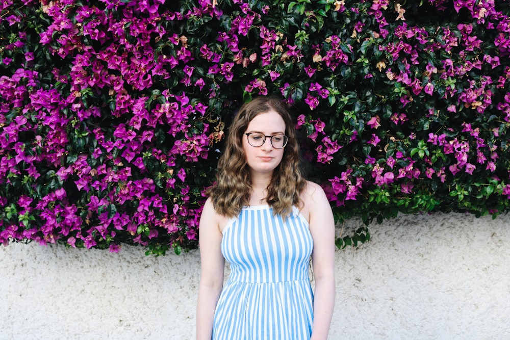 woman wearing blue dress standing in front of purple flowers