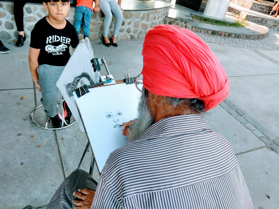 A close-up photo of Israel Tanzondo deeply focused while sketching a realistic portrait in his minimalist studio.