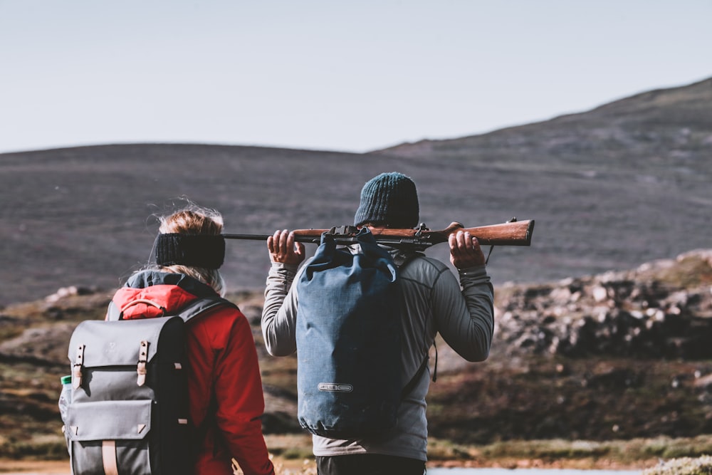 man holds rifle beside woman