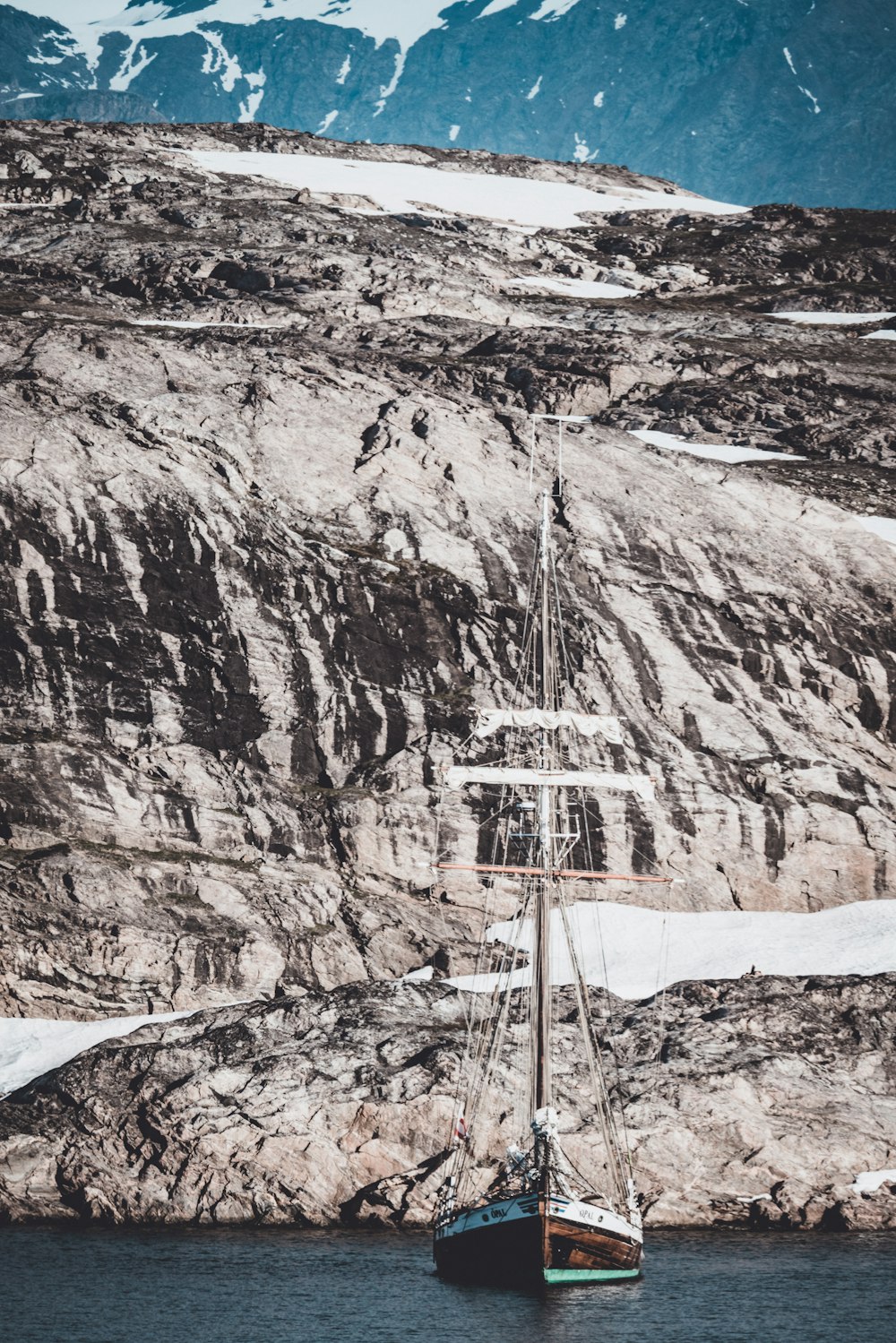 boat sailing near snow covered mountain