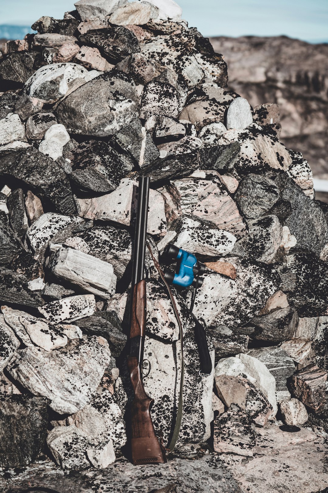 brown rifle beside rocks