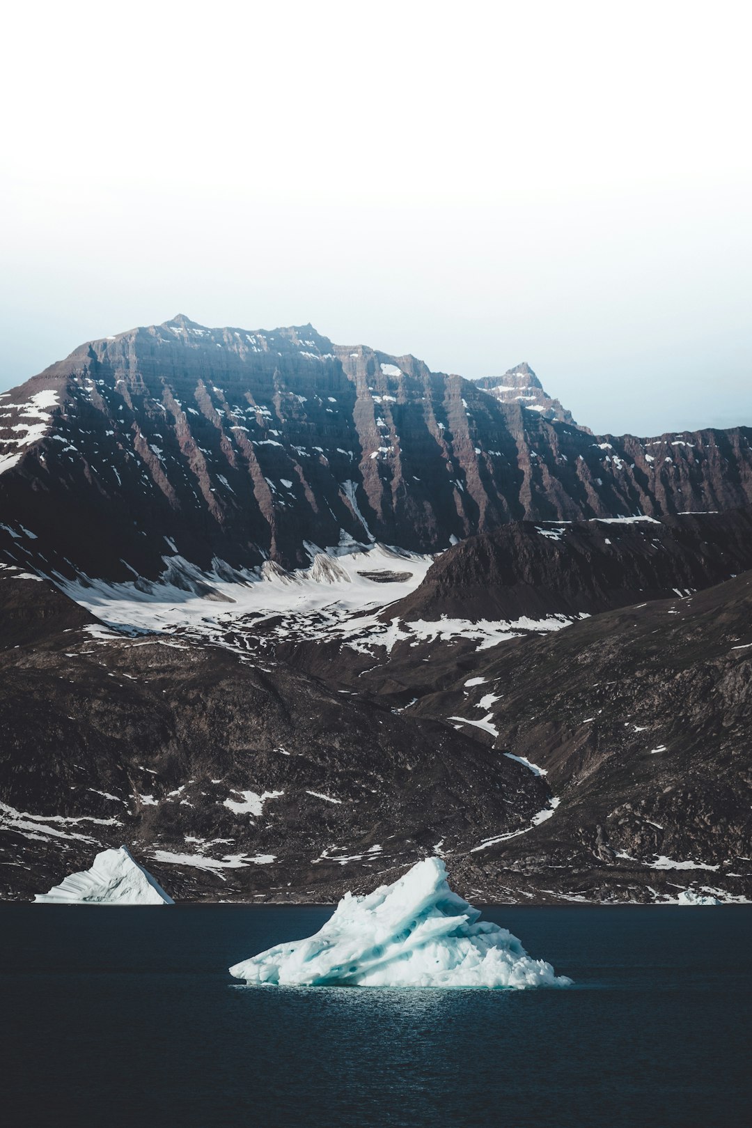icebergs on sea near mountains during daytime