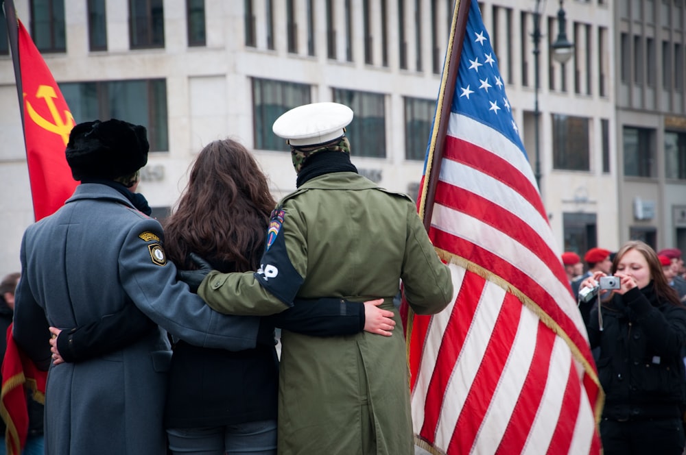 two men and woman standing behind of U.S. flag