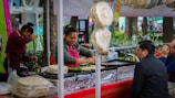 Paulo Roberto serving happy customers at a busy outdoor food stand.