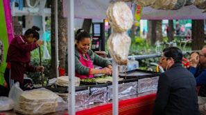 Paulo Roberto serving happy customers at a busy outdoor food stand.