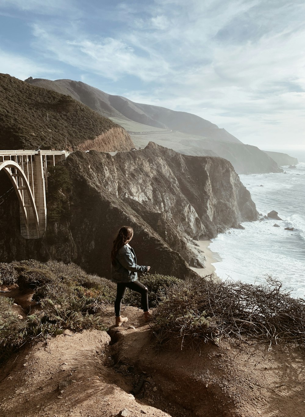 woman standing on top of mountain looking at sea