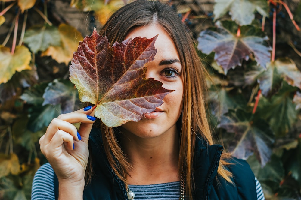 woman covering right eye with maroon maple leaf