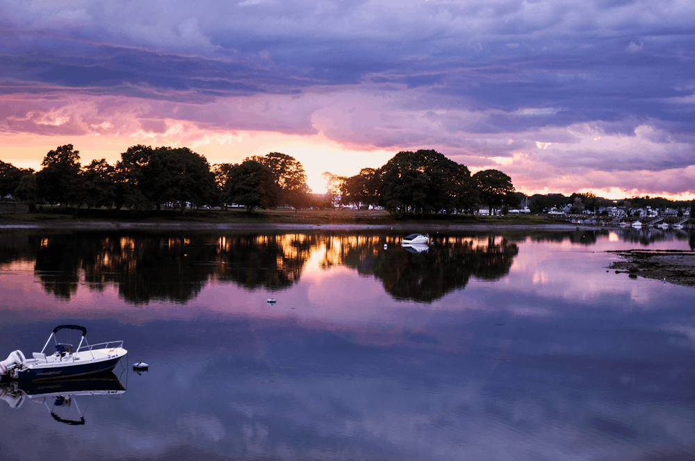 a boat floating on top of a lake under a cloudy sky