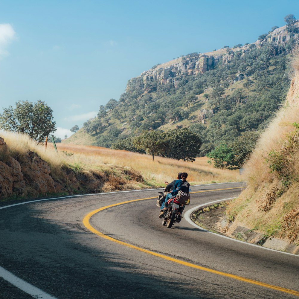 man and woman riding motorcycle on curving road during daytime