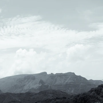 A serene landscape painting featuring rolling hills under a cloudy sky.