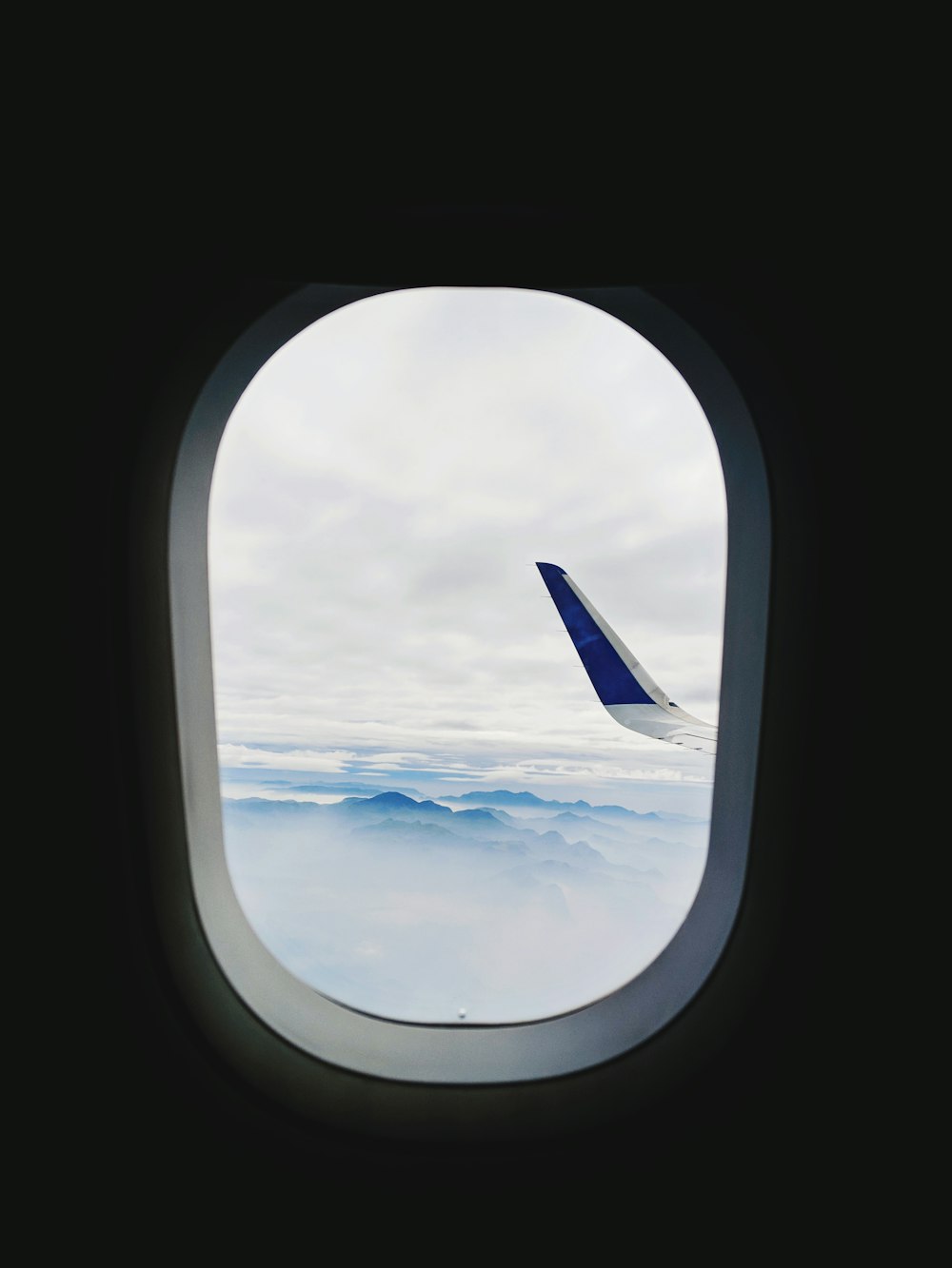 Blau lackierte Flügelspitze eines Verkehrsflugzeugs durch das Fenster gesehen