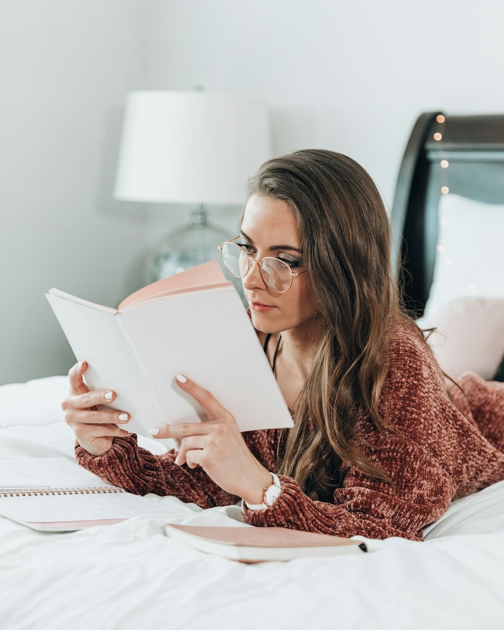 woman lying on bed while reading book